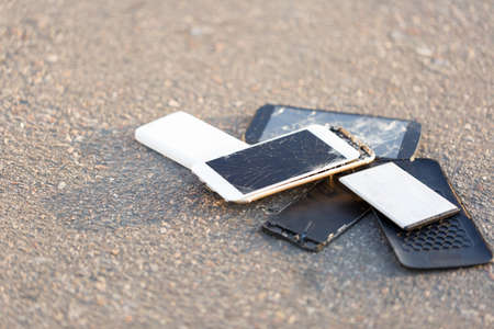 The broken mobile phones are on asphalt.