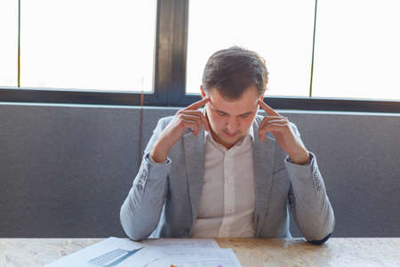 A guy, an office worker, studies documents, and holds hands behind head.の写真素材