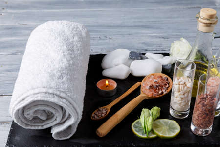 White towel, pebbles and aroma oil for spa procedures on a dark surface.の写真素材