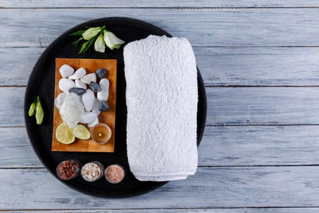 On a wooden background is a round board with a things for the spa and aroma procedures.