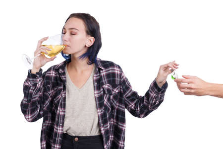 A young girl, drinks wine from a glass and gives the keys to someone. Isolated on white.の写真素材