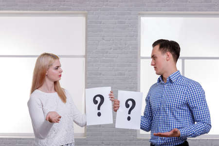 Two serious people, a guy and a girl, are holding a leaf with a question mark and looking at each...