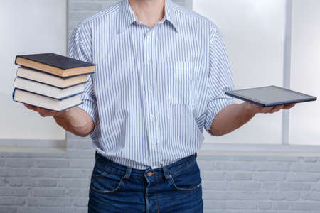 A guy in one hand holding a stack of books and a tablet.の写真素材