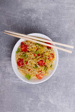 Chinese noodles with tomatoes and greens. On a worn stone surface.の写真素材