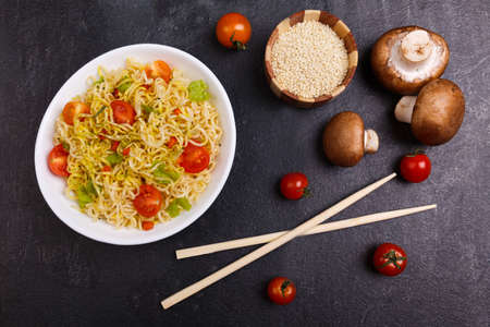 On the table a serving of pasta, tomatoes, mushrooms and chopsticks.の写真素材