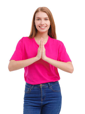 A smiling young girl, in a pink T-shirt, put her hands together at the chest level. Isolated on white.の写真素材