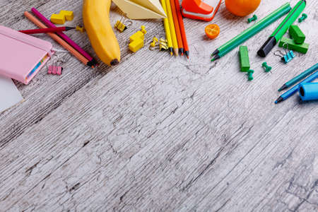 On the table are scattered colorful chancellery and a banana with mandarin. With a place for an inscription.の写真素材