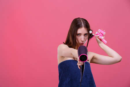A playful girl , in a blue towel, with hair curlers, holds fenperide in her arms.の写真素材