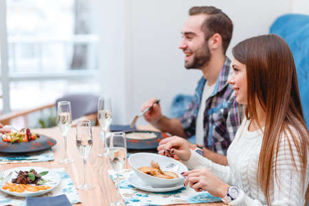 A group of people in a cafe, eating, drinking and talking.の写真素材