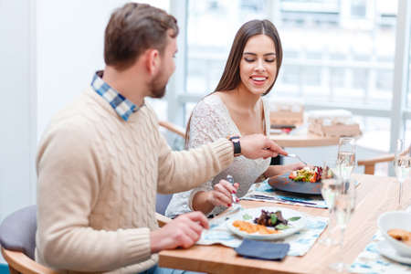 A couple in love sit in a cafe and try each others food.の写真素材