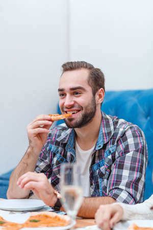 A happy guy eats a slice of pizza and smiles.の写真素材