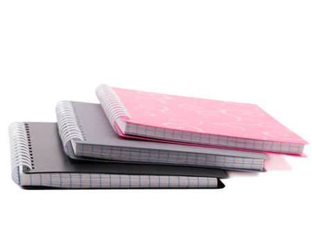 A stack of three notepads of pink, gray and black with spiral binding of sheets. Isolated on white background.の写真素材