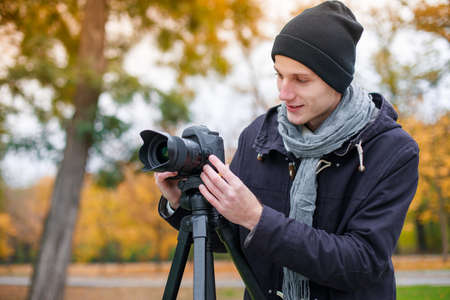 A guy in the park sets up the camera on a tripod.の写真素材