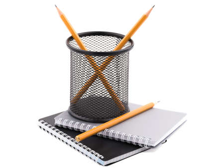 Two black and gray notepad with spiral fastening sheets on which there is a black container in a mesh with pencils inside. Isolated on white background. Close-up.の写真素材
