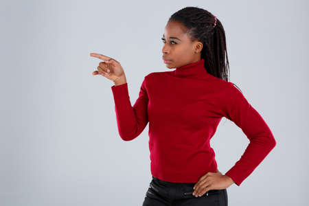 A girl, Afro-American, with a pensive look looks to the side showing the index finger in front of her.の写真素材