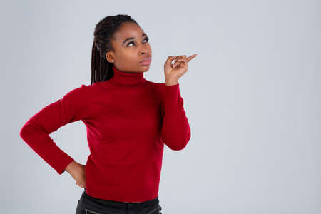 Serious african american girl with a pensive look looking up showing her index finger.の写真素材