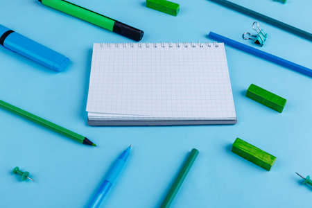 Notepad and various pencils, markers and stationeryare placed on a blue background.の写真素材