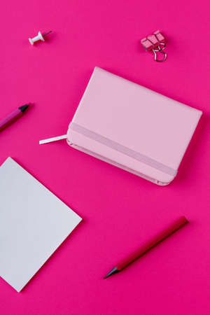 Notepad, pencils and clips, on a pink background. View from above.の写真素材