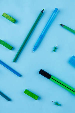 Pens, pencils, markers, buttons and crayons, layout on a blue background. View from above.の写真素材