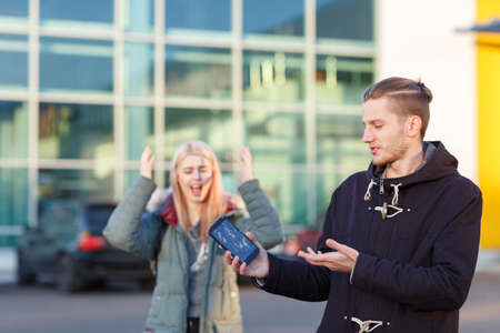 A guy holds a broken mobile phone, a girl screams in the background and gestures with her hands.の写真素材