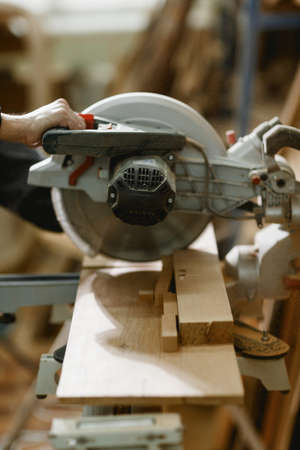 The process of cutting a wooden bar with a lathe is followed by an carpenter man. Indoors.の写真素材