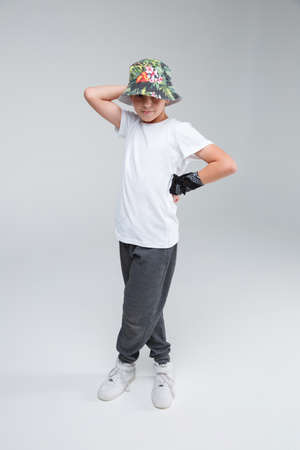 A guy is a teenager, standing with his legs crossed, one hand on the belt and the second behind his head.の写真素材