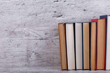 Several different colorful thick books are laid out on a wooden background. Close-up. The concept of...