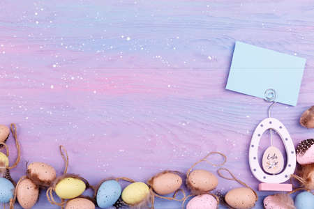 Heap of Quail eggs with feathers on a lavender wooden background with copy space for text. Easter...