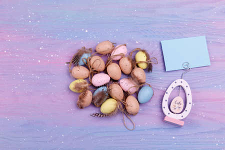 Heap of Quail eggs with feathers on a lavender wooden background with copy space for text. Easter...