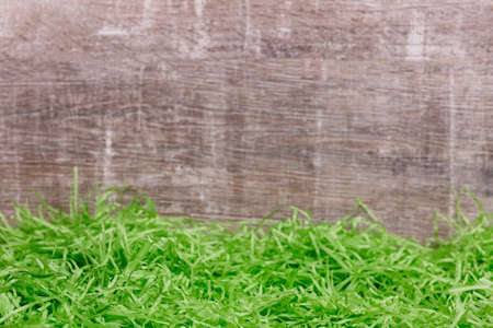 Beautiful green grass in front of a wooden background. Easter greeting card. Copy space for the...