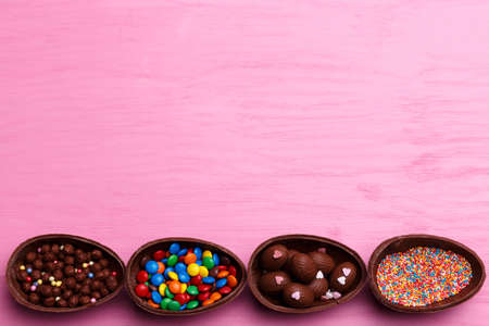Chocolate Easter eggs and colorful candies on a bright pink background. Easter sweets concept.