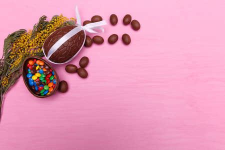 Chocolate Easter eggs and colorful candies on a bright pink background. Easter sweets concept.の写真素材
