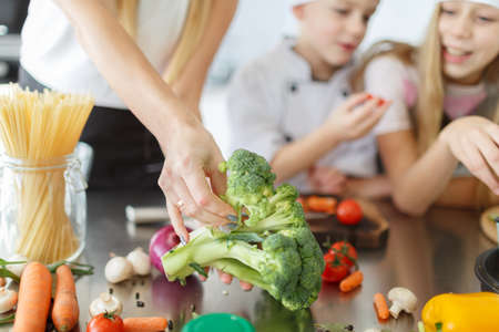 A family cooking a healthy dish from broccoli and other vegetables in the kitchen room. Organic food concept.の写真素材