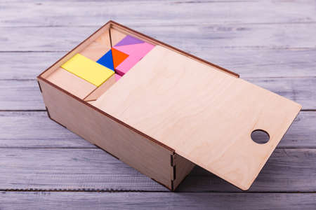 Educational games for children. Red, yellow, pink, blue geometrical figures on the wooden background. Entertaining objects. Close-up. Entertainment concept.の写真素材