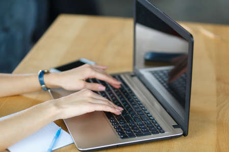 Top view of young female hands working on her laptop. Businesswoman printing on a laptop. Business concept.の写真素材