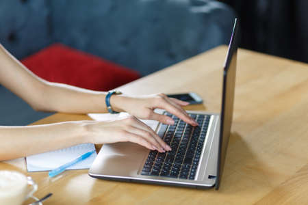 Top view of young female hands working on her laptop. Businesswoman printing on a laptop. Business...