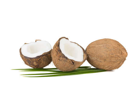A close-up picture of chopped in half and whole coconuts isolated on white background. The concept of exotic fruits with leaves full of vitamins.の写真素材