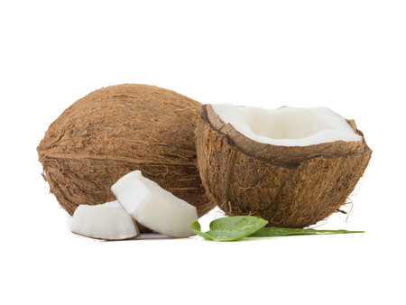 A close-up picture of chopped in half and whole coconuts isolated on white background. The concept of exotic fruits with leaves full of vitamins.の写真素材