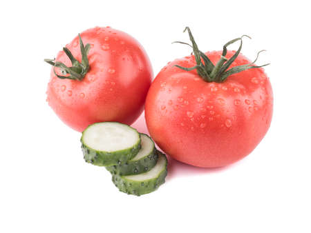 Fresh autumn vegetables isolated on a white background. Sliced green cucumbers, a juicy and whole tomato. Ingredients for saladの写真素材
