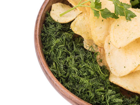 Closeup of crispy potato chips with fresh greens in a brown plate on a white background. Junk food concept. Top view of a fast snack.の写真素材