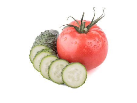 Fresh autumn vegetables isolated on a white background. Sliced green cucumbers, a juicy and whole tomato. Ingredients for saladの写真素材