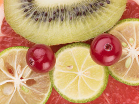 A red sliced grapefruit, lime and fresh kiwi with seeds as background. A concept of citrus fruits full of vitaminsの写真素材