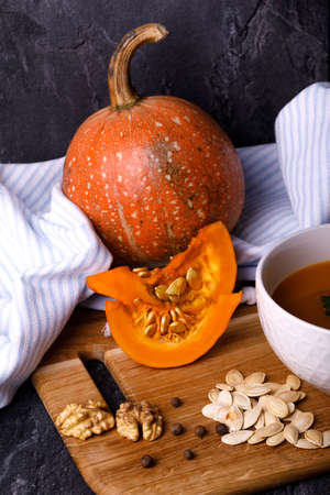 Close-up of Halloween pumpkin with a plate of gourd soup on a dark background. The concept of autumn holidays and seasonal harvestの写真素材