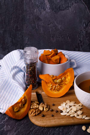 Close-up of Halloween pumpkin with a plate of gourd soup on a dark background. The concept of autumn holidays and seasonal harvestの写真素材