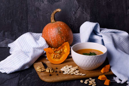 Close-up of Halloween pumpkin with a plate of gourd soup on a dark background. The concept of autumn holidays and seasonal harvestの写真素材