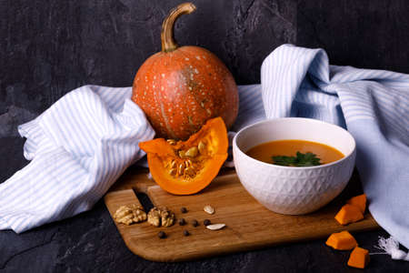 Close-up of Halloween pumpkin with a plate of gourd soup on a dark background. The concept of autumn holidays and seasonal harvestの写真素材