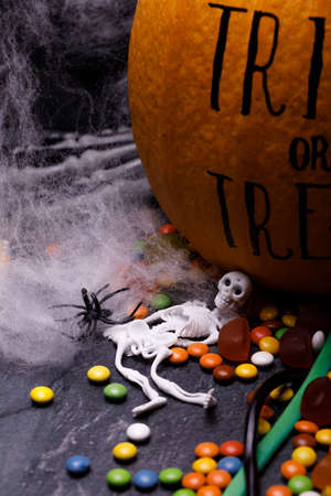Halloween pumpkin with sweet candies on a dark background. The concept of autumn holidays, close-up. Lettering trick and treat on a gourd.の写真素材