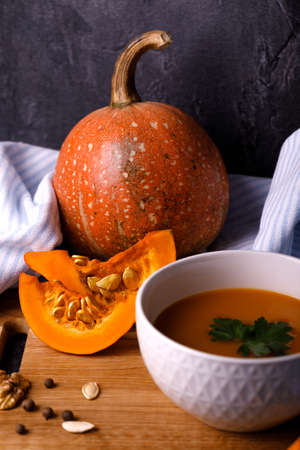 Close-up of Halloween pumpkin with a plate of gourd soup on a dark background. The concept of autumn holidays and seasonal harvestの写真素材