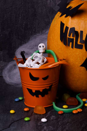 Halloween pumpkin with candles, spiders, web, sweets, horror stories on a dark background, closeup. The concept of autumn holidays.の写真素材