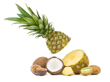 A sliced ripe and tropical pineapple, juicy passion fruit, kiwi and halved coconut pieces isolated on a white background.の写真素材